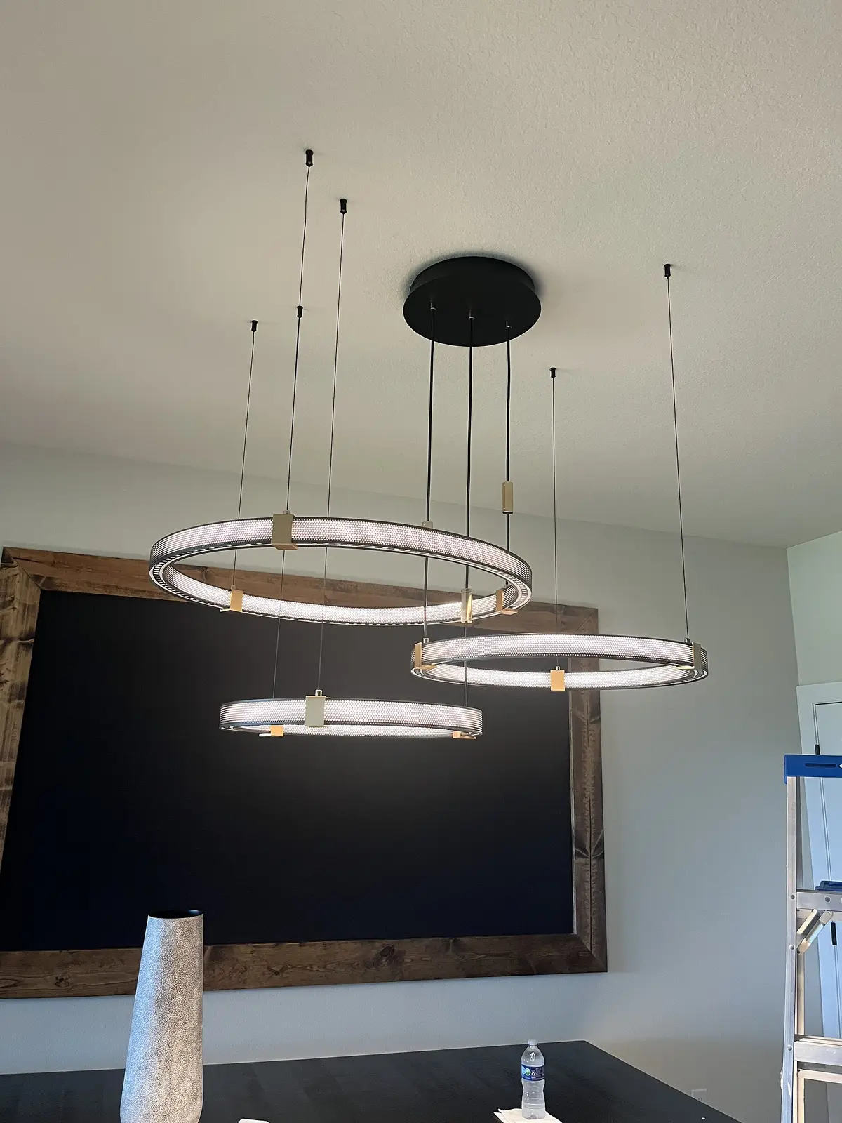 Layered modern ring pendant above a dining table