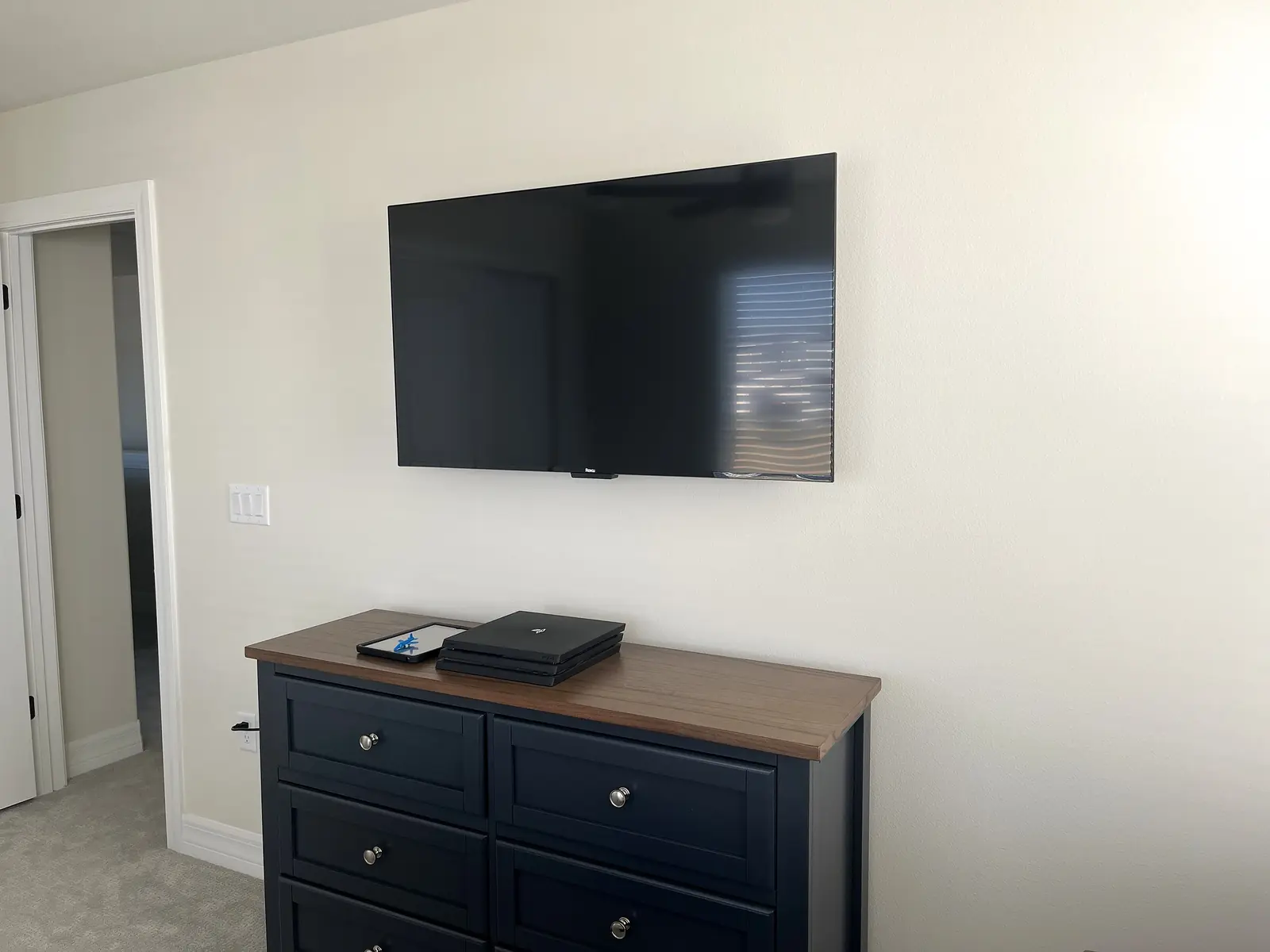 Wall-mounted television positioned above a guest-room dresser