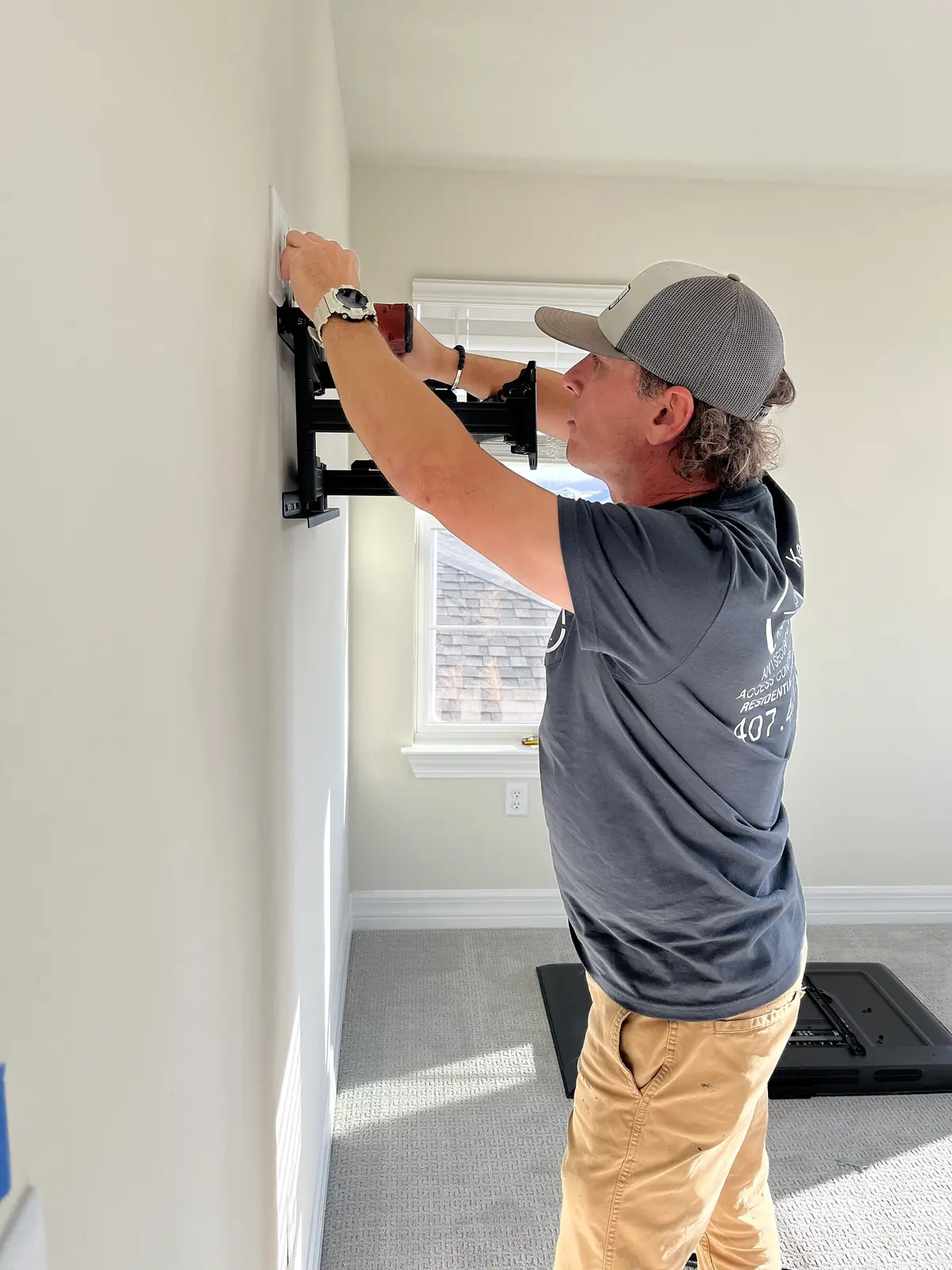 Technician aligning a wall bracket before mounting a television